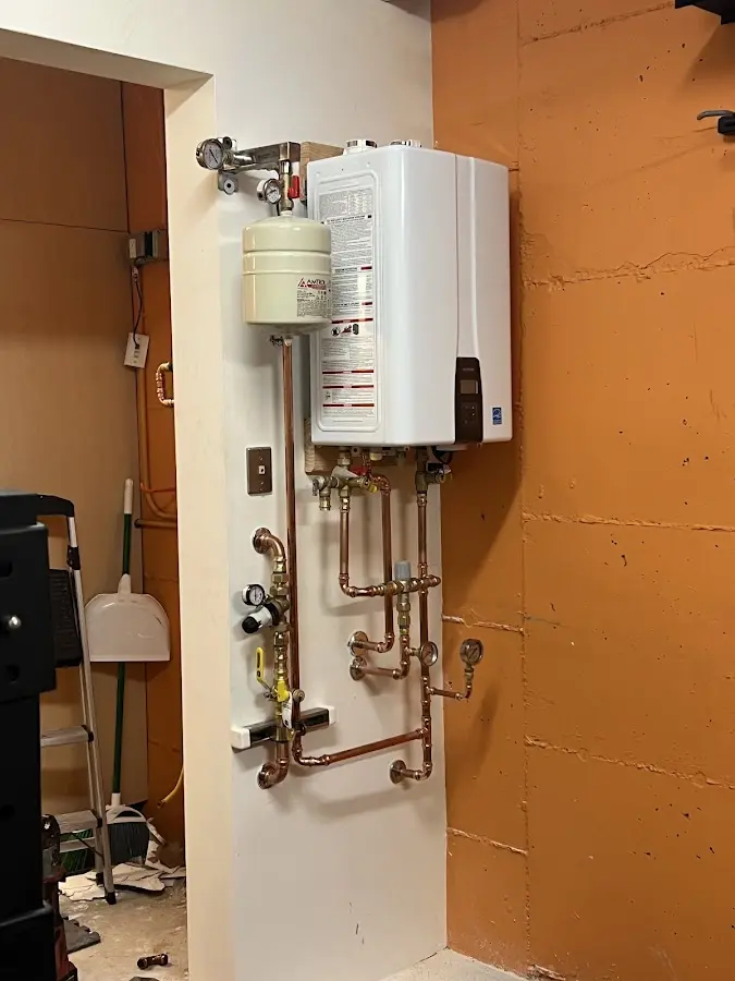Plumbing technician inspecting water heater connections in New Ipswich